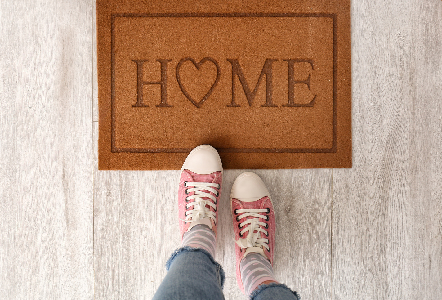 Person Standing near Door Mat on Floor in Hallway