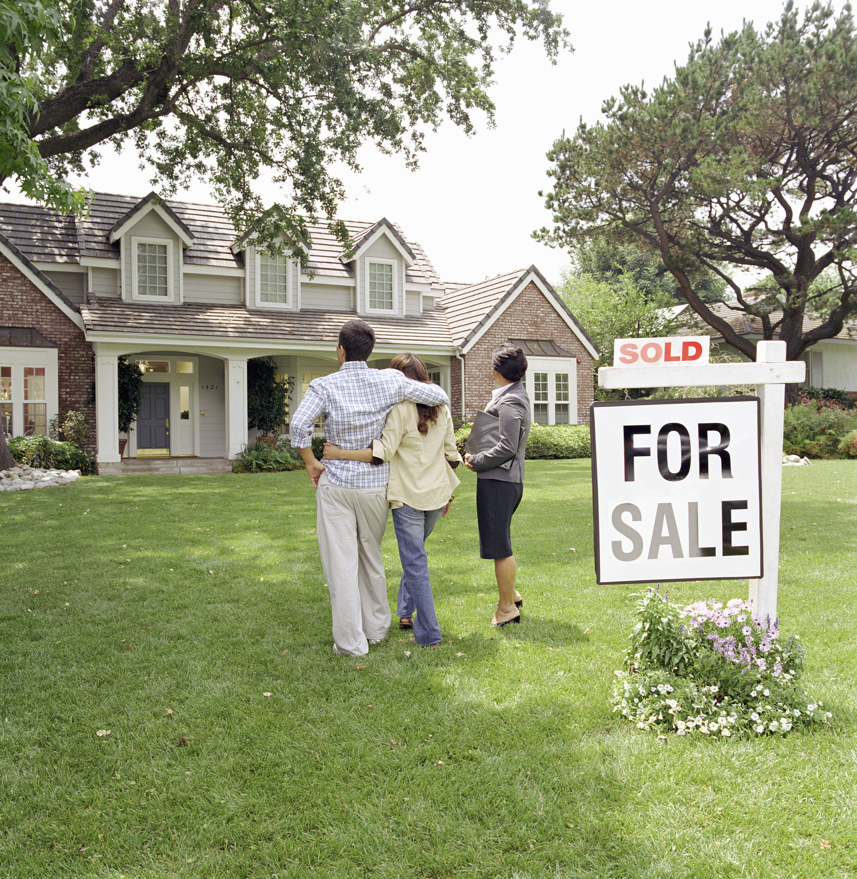 Realtor standing with couple in front of house